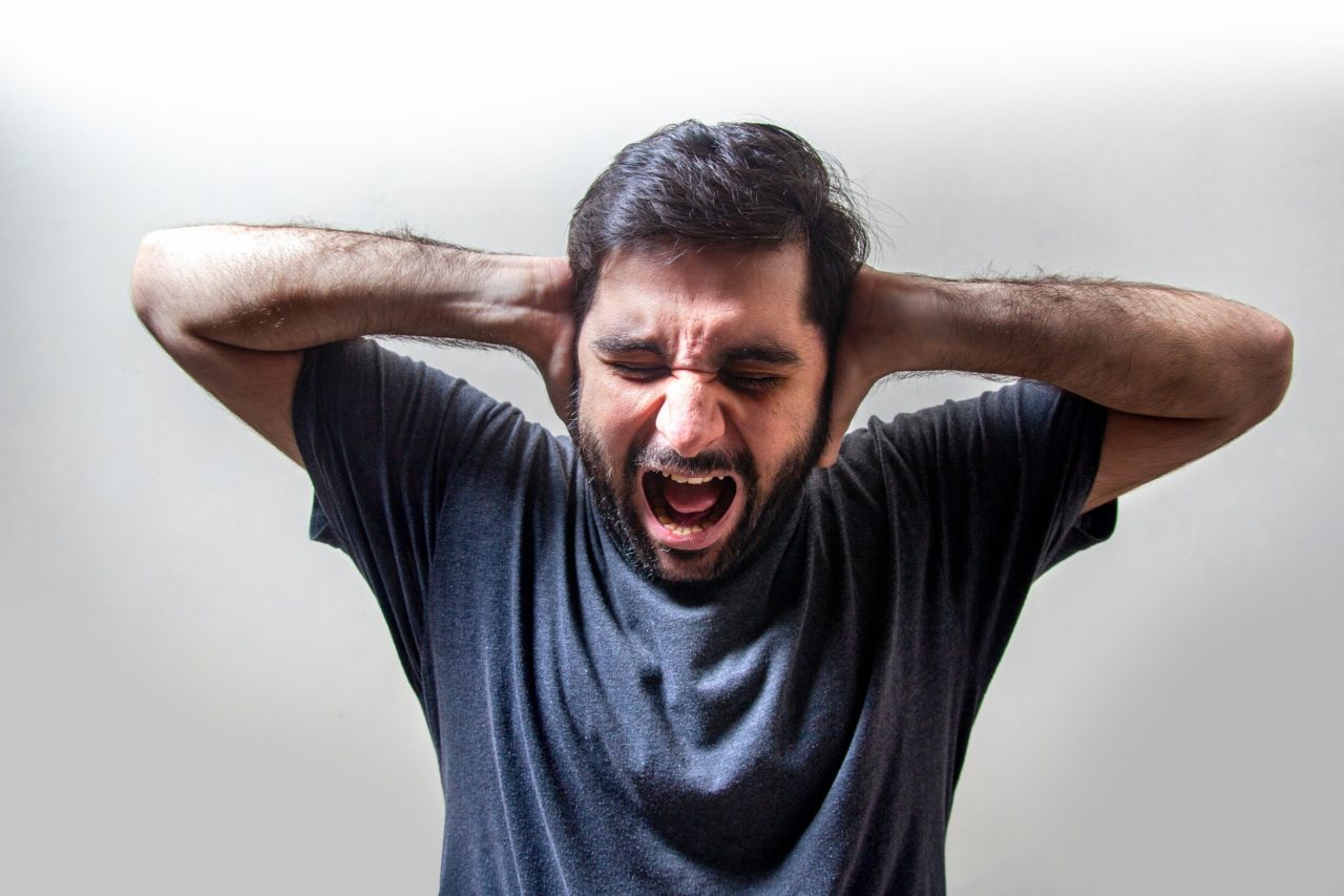 בחור צעיר ברגע חרדה שם ידיים על האוזניים - אילוסטרציה